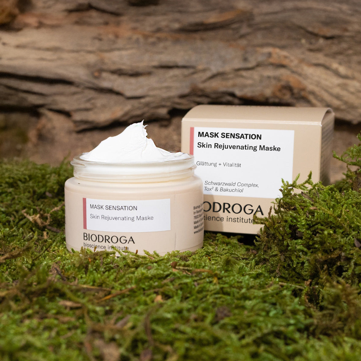 Die Skin Rejuvenating Maske als Tiegel und Faltschachtel auf Moos und im Hintergrund ist Holz zusehen