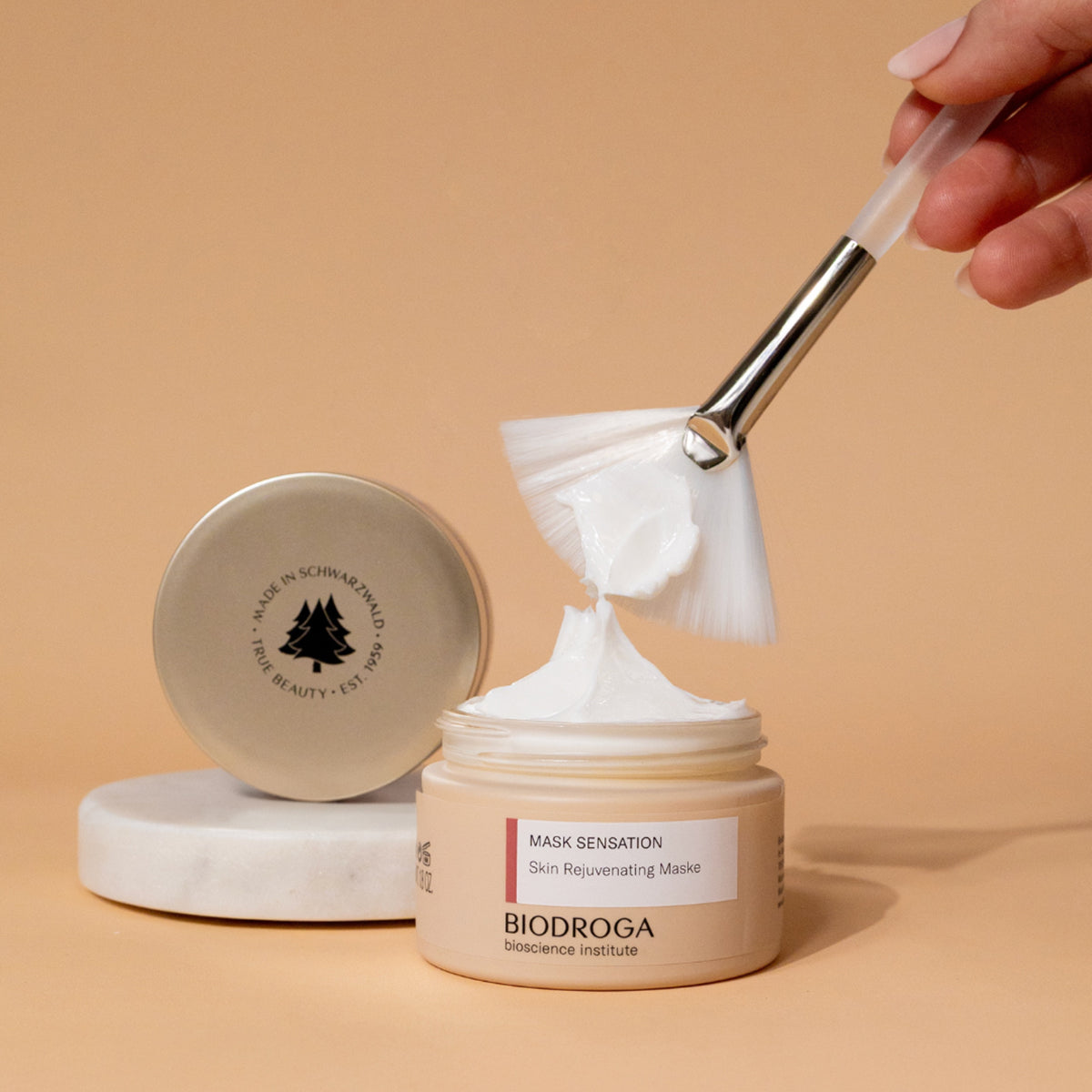 Tiegel der Skin Rejuvenating Maske ist offen und ein Pinsel zeigt die Textur der Creme